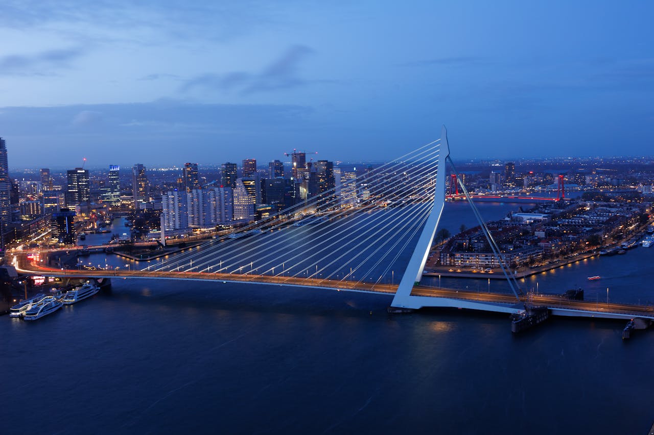 A breathtaking view of Rotterdam's Erasmus Bridge and skyline at twilight, showcasing modern urban architecture.